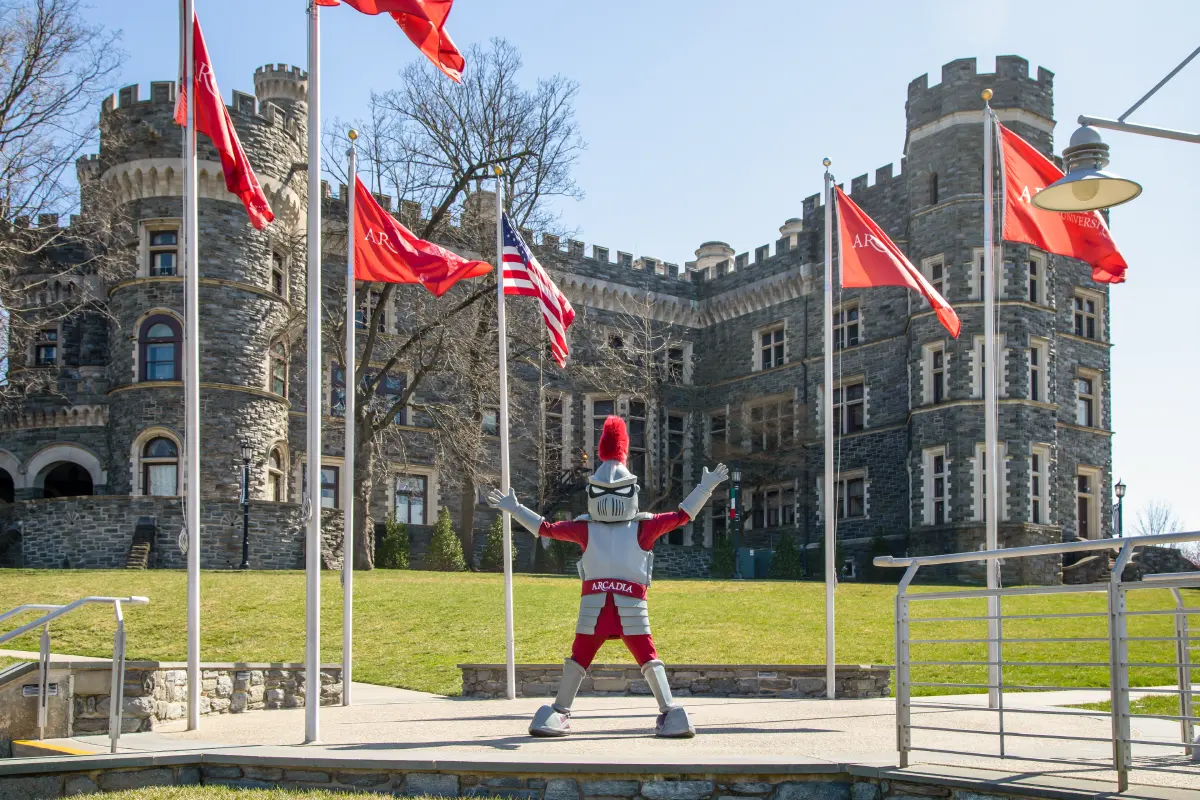 Knight Mascot in front of Arcadia flags with Grey Towers Castle in the background