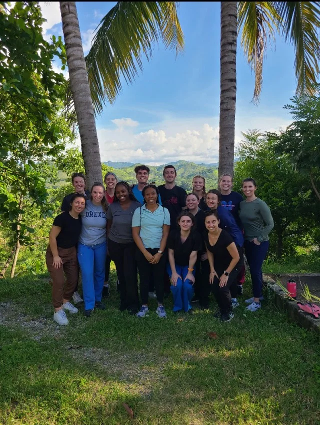 A group of student posing under palm trees