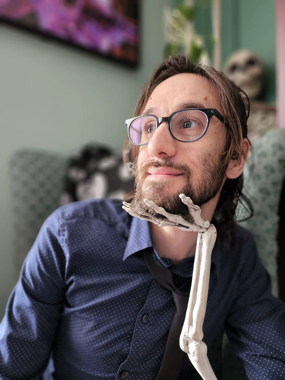 Nick Perilli, writer and librarian, with a skeleton hand holding up his chin.