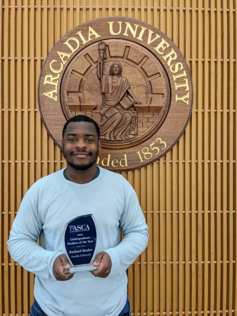 Rasheed Booker standing with his ASCA award.