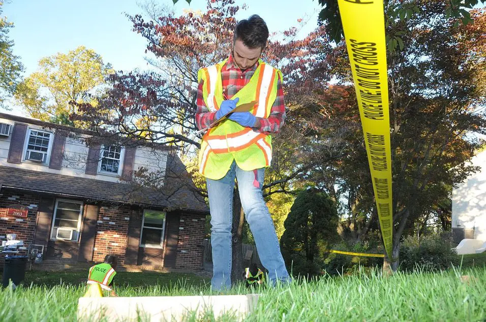 A man takes notes during a forensics investigation at the crime scene house.