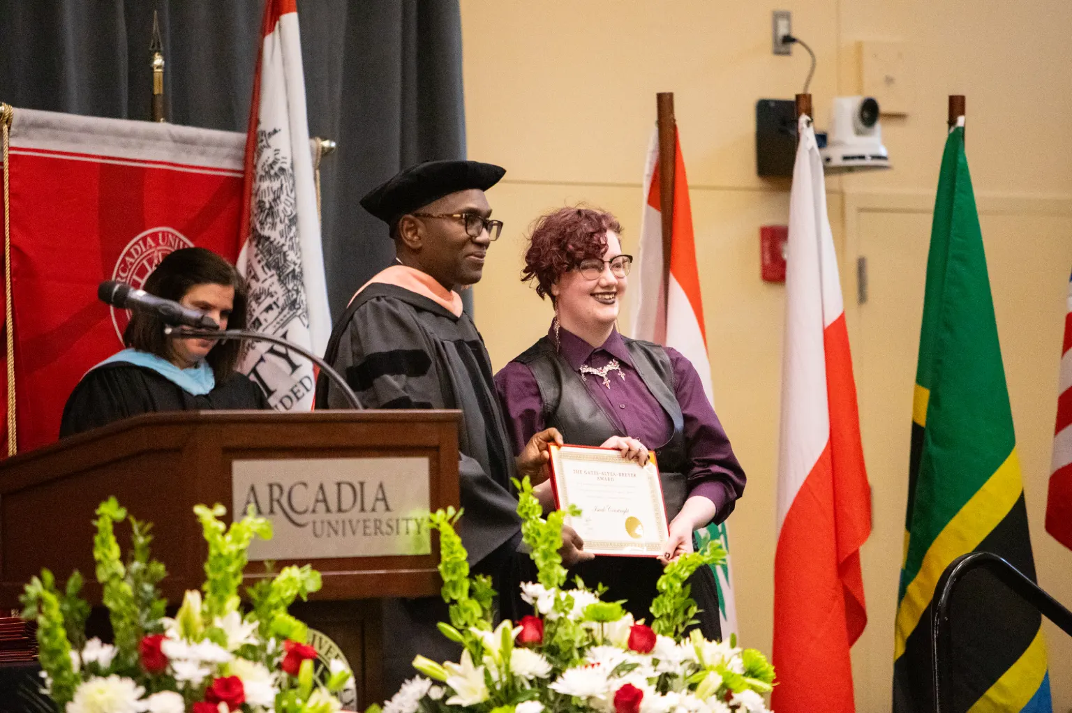 A student holding up their award with faculty member