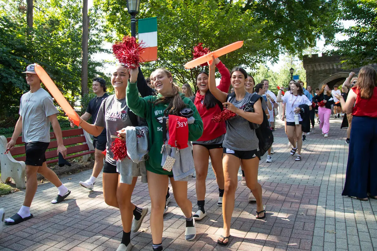 Student athletes walking down the Walk of Pride with pom-poms from Grey Towers