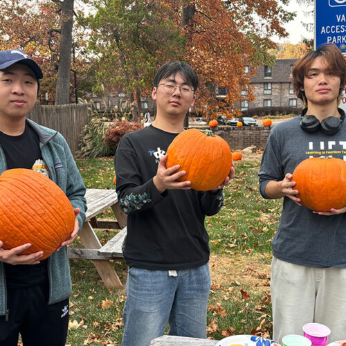 Three people holding pumpkins in their hands