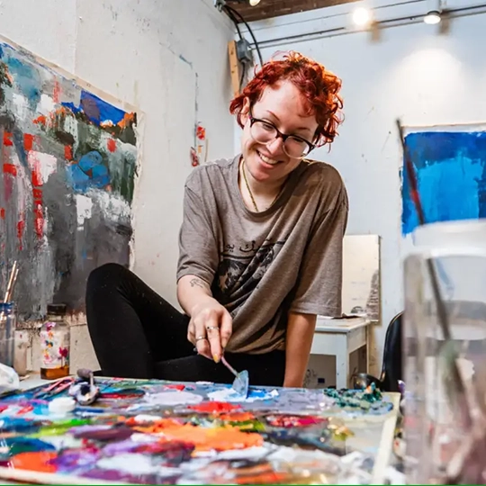 An artist workes with oils on a palette in a studio on campus.