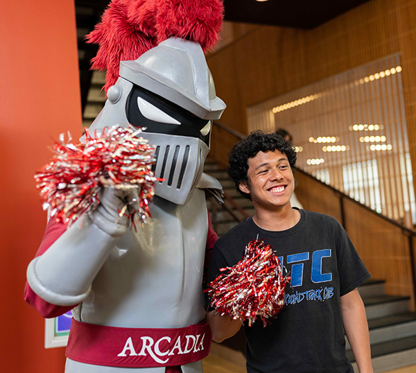 Archie holds pompoms as a student stand alongside.