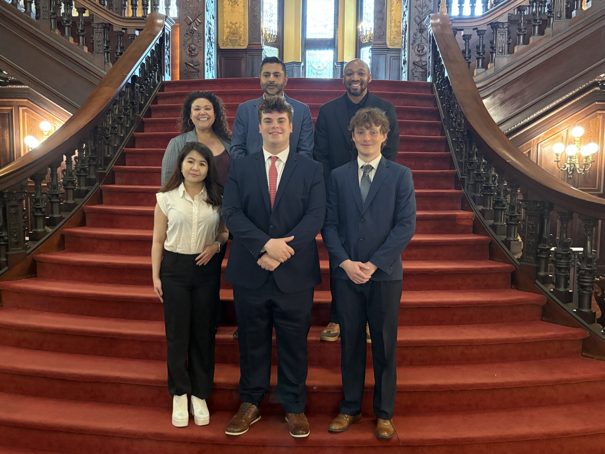A group of Arcadia staff and students assembled on the grand staircase in Grey Towers Castle. Top row (L-R): Christine Storch, President Ajay Nair, Dr. Donavan McCargo. Bottom row (L-R): Nelly Tyncherova, Carter Mostecki, Jacob Mann