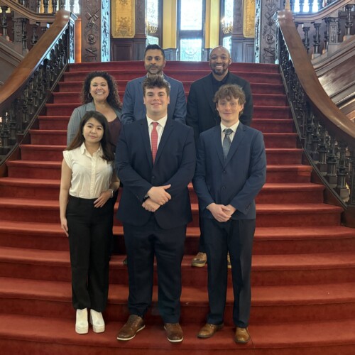 A group of Arcadia staff and students assembled on the grand staircase in Grey Towers Castle. Top row (L-R): Christine Storch, President Ajay Nair, Dr. Donavan McCargo. Bottom row (L-R): Nelly Tyncherova, Carter Mostecki, Jacob Mann