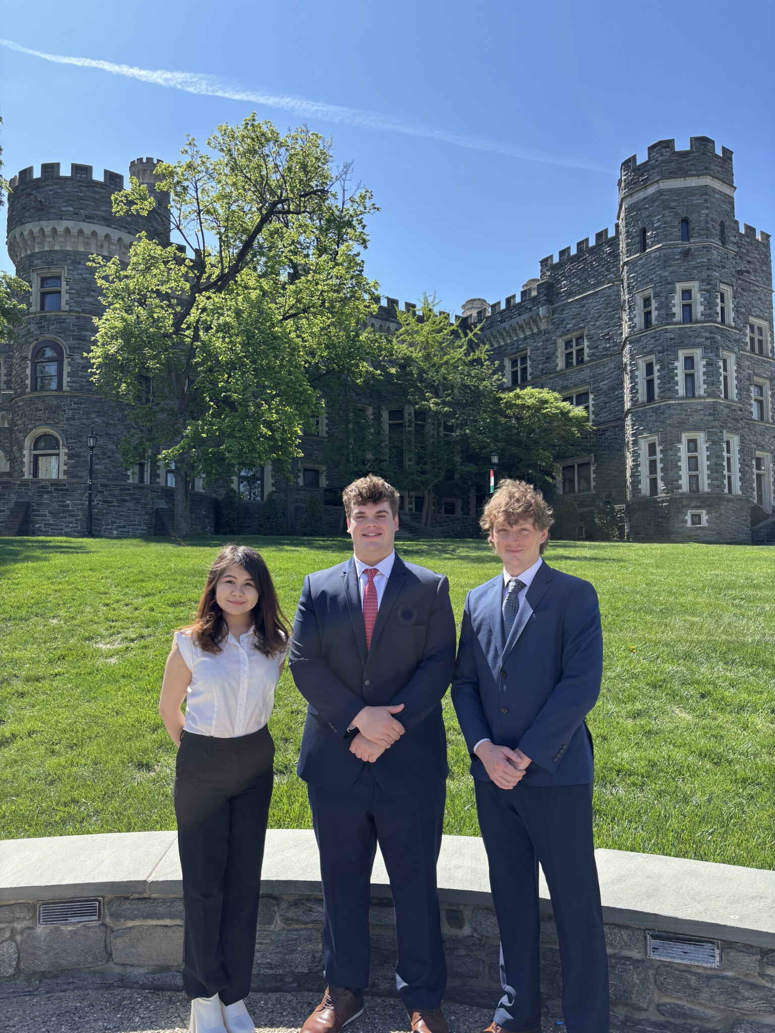 Three students standing on Haber Green in front of the Castle