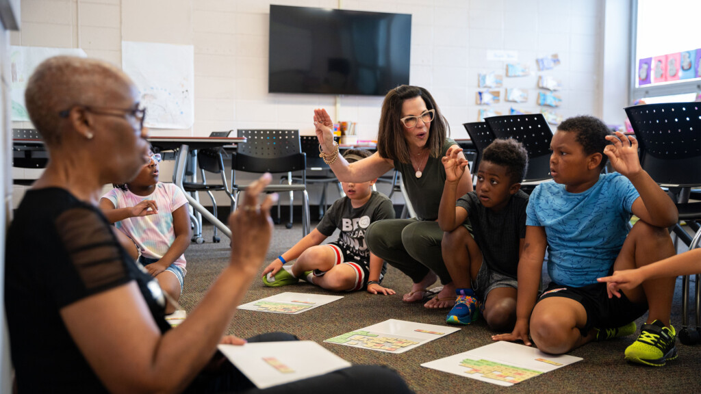 Two special education teachers on floor with students during circle time