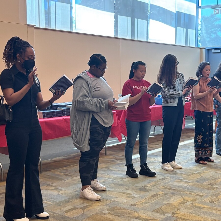 Members of the Arcadia community standing in the front of the room reading “Amari and the Night Brothers.”
