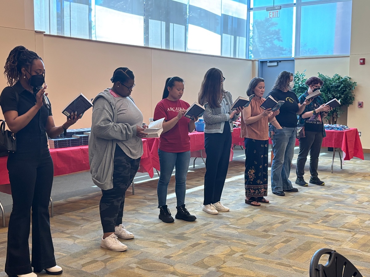 Members of the Arcadia community standing in the front of the room reading “Amari and the Night Brothers.” 