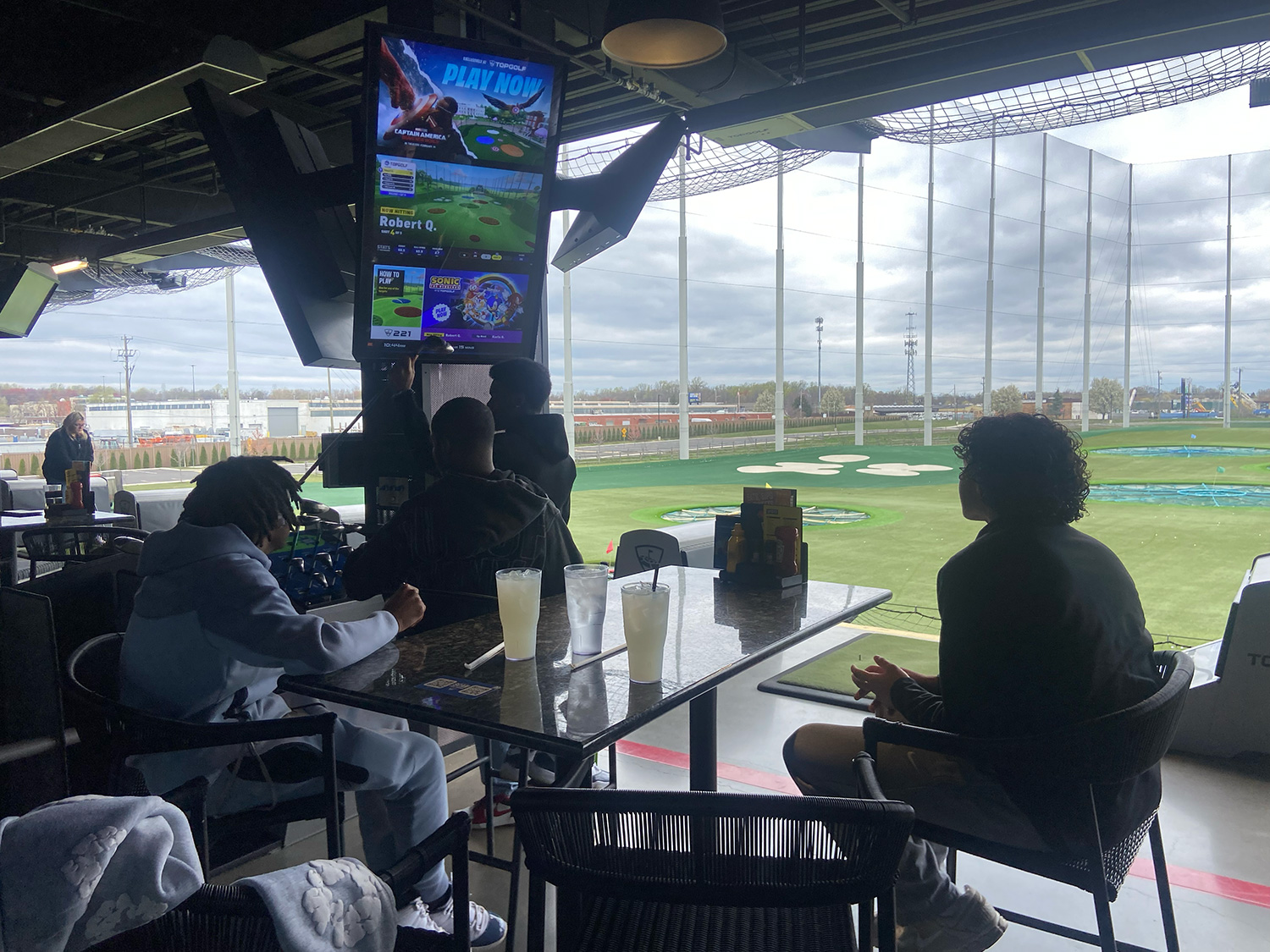 AIMS students looking at the Top Golf scoreboard.