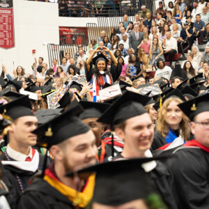 A student making a heart from their hands in the crowd.