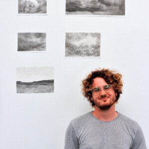 Wilkes ’25 in front of his photos.