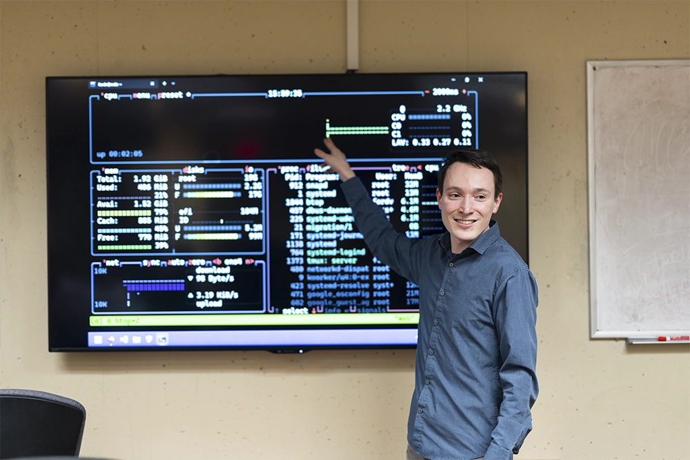 An instructor points to a large wall computer board.