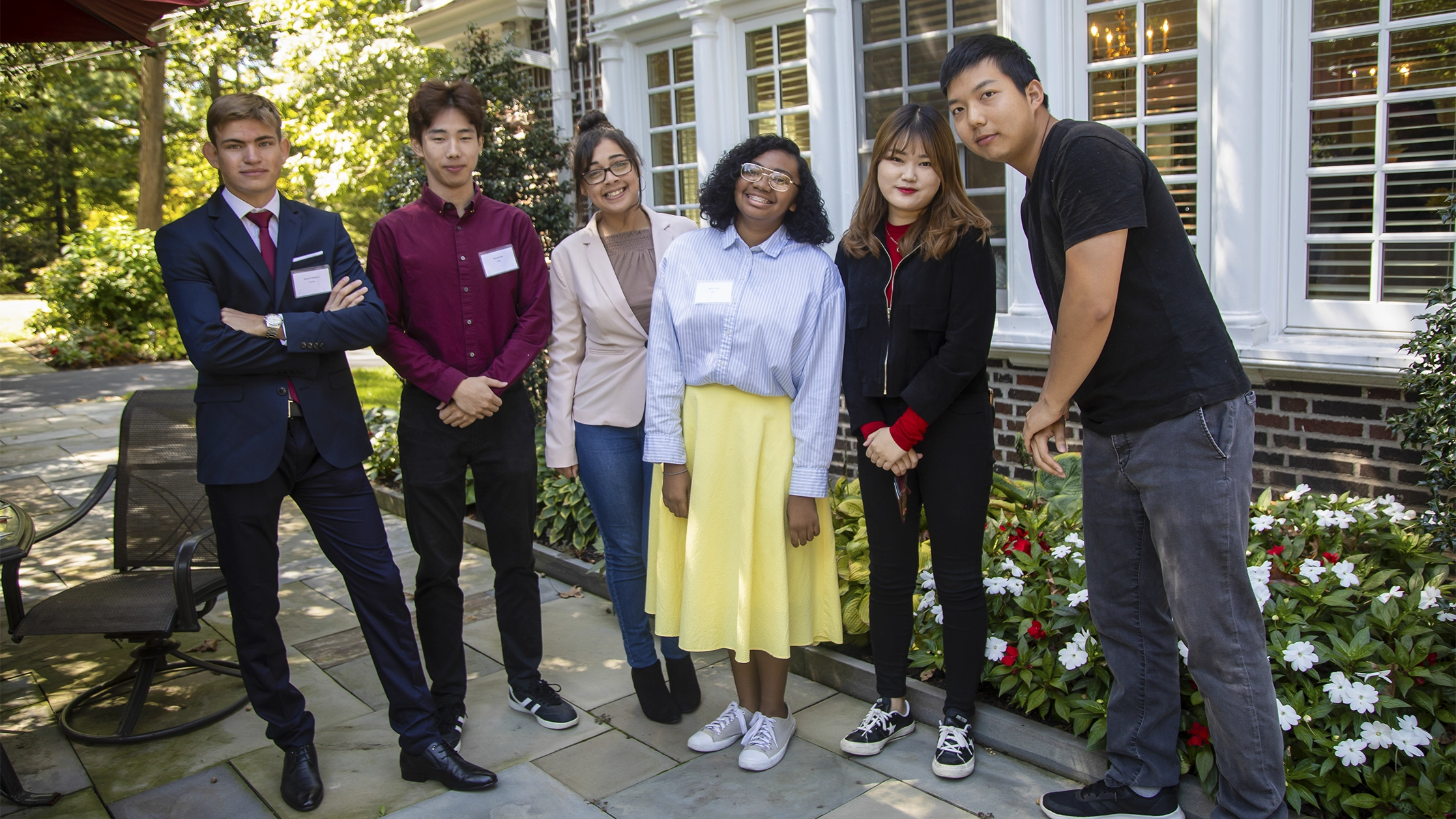 Six students stand in front of President Nair's home during their international students luncheon.