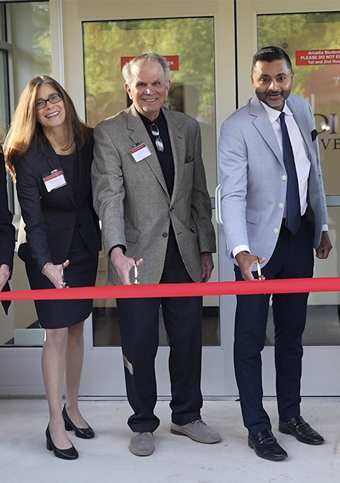 John Rollins, center, cuts a red ribbon for the Royal Ave. opening.