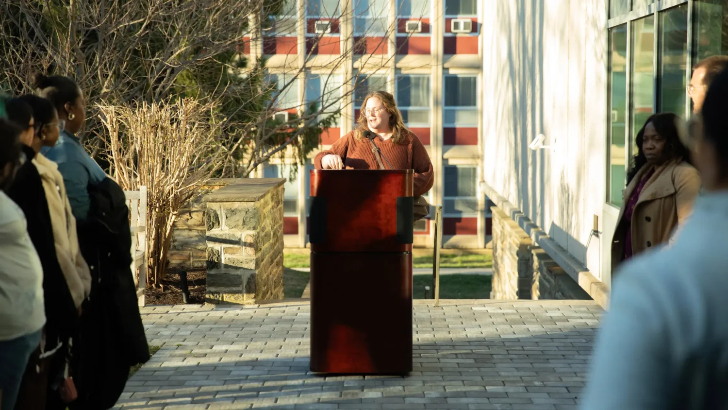 A woman addresses people at a podium on the Arcadia campus.