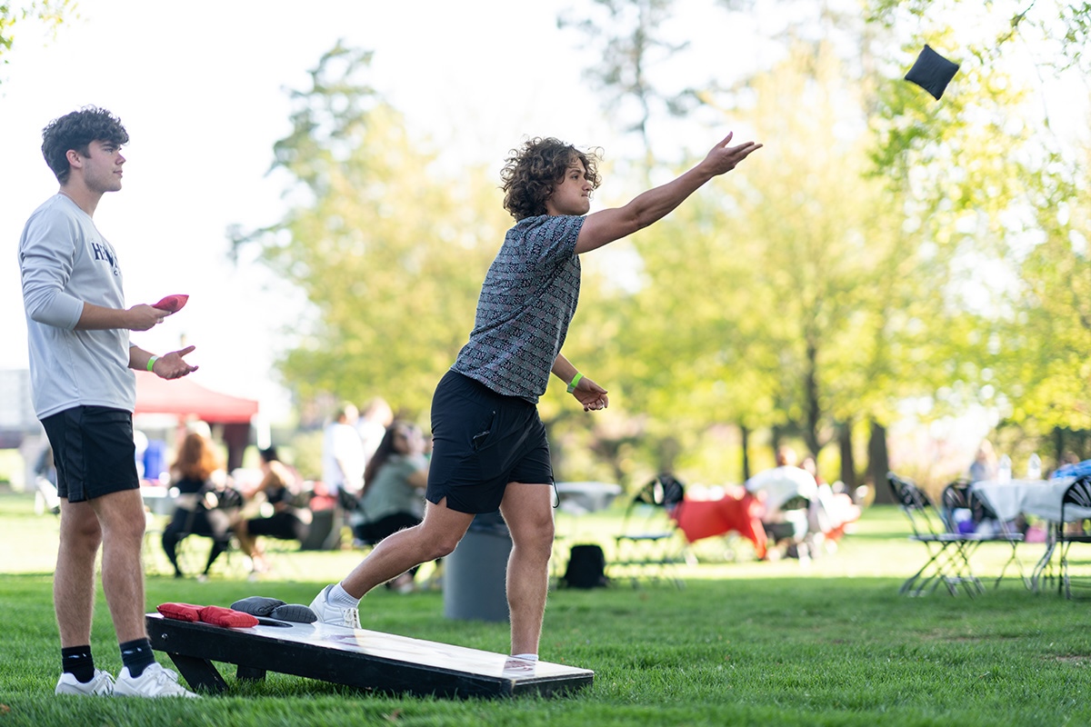 Two Arcadia University students play cornhole on Haber Green