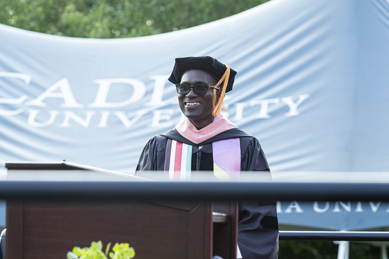 Alex Otieno stands behind a podium on stage during commencement 2023.
