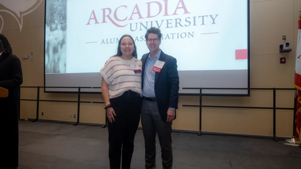 Man and woman stand on stage after woman receives award.
