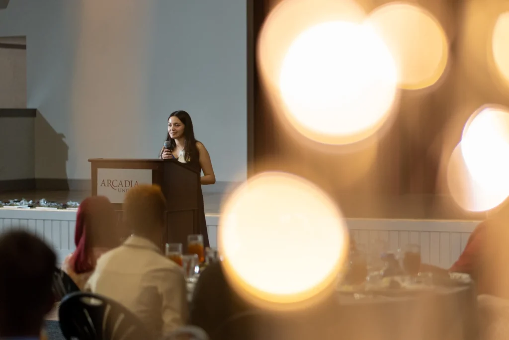 Young woman at the podium holding a microphone and talking.