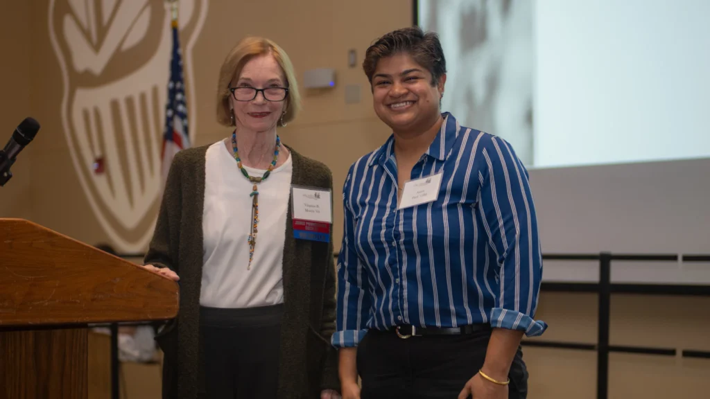 Two women on stage smiling after woman on the right won the award.