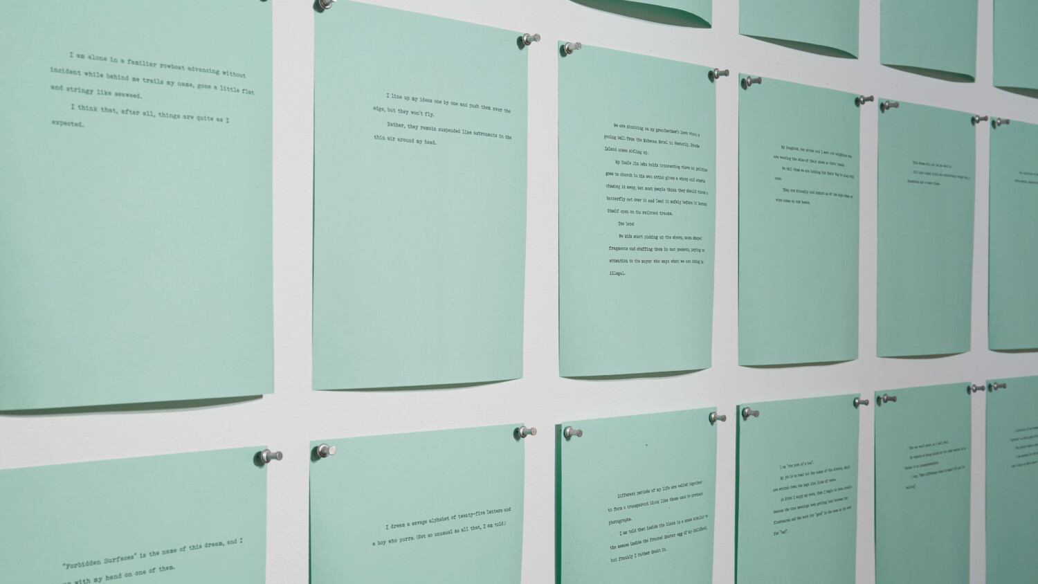 teal sheets of paper with typewriter text arranged in a grid