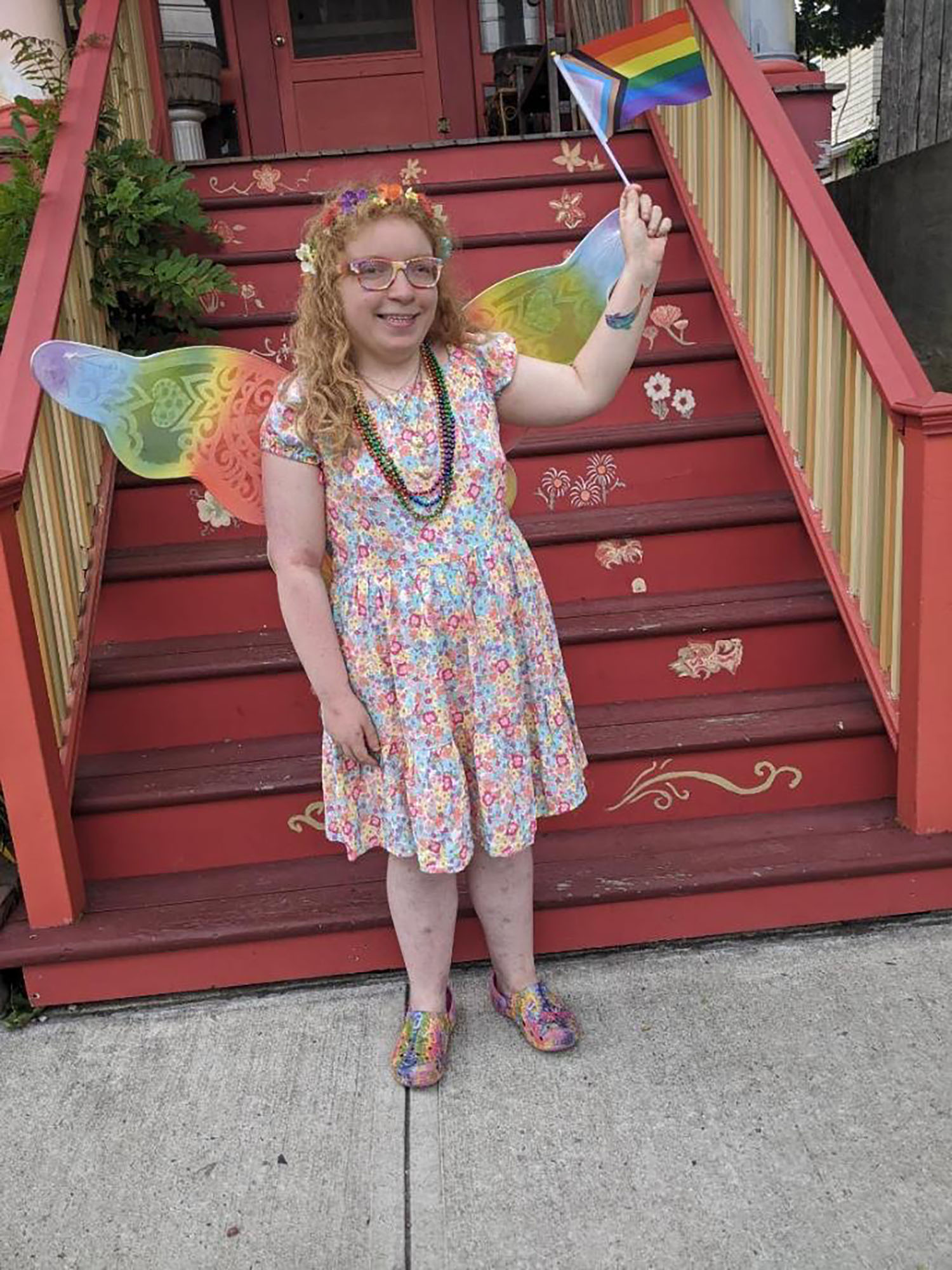 Parlin Gressitt ’26 waving a LGBTQIA+ flag in front of some stairs.