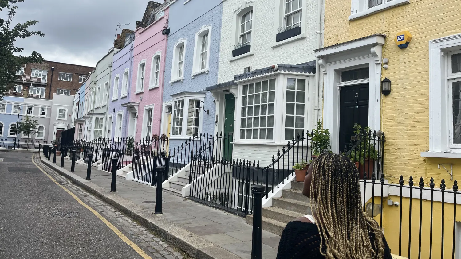 An Arcadia student walks down a sidewalk in a neighborhood of pastel-colored houses in London, England.