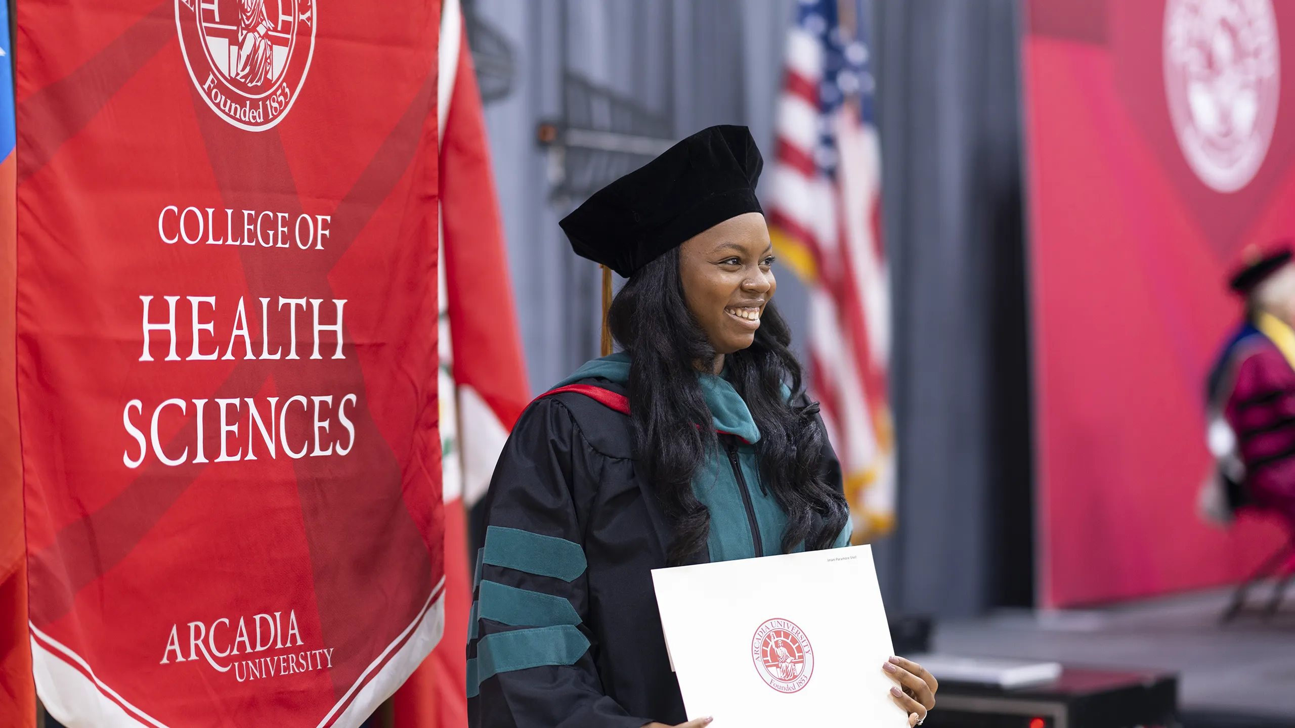 A DPT graduate proudly holds their diploma during a commencement ceremony.