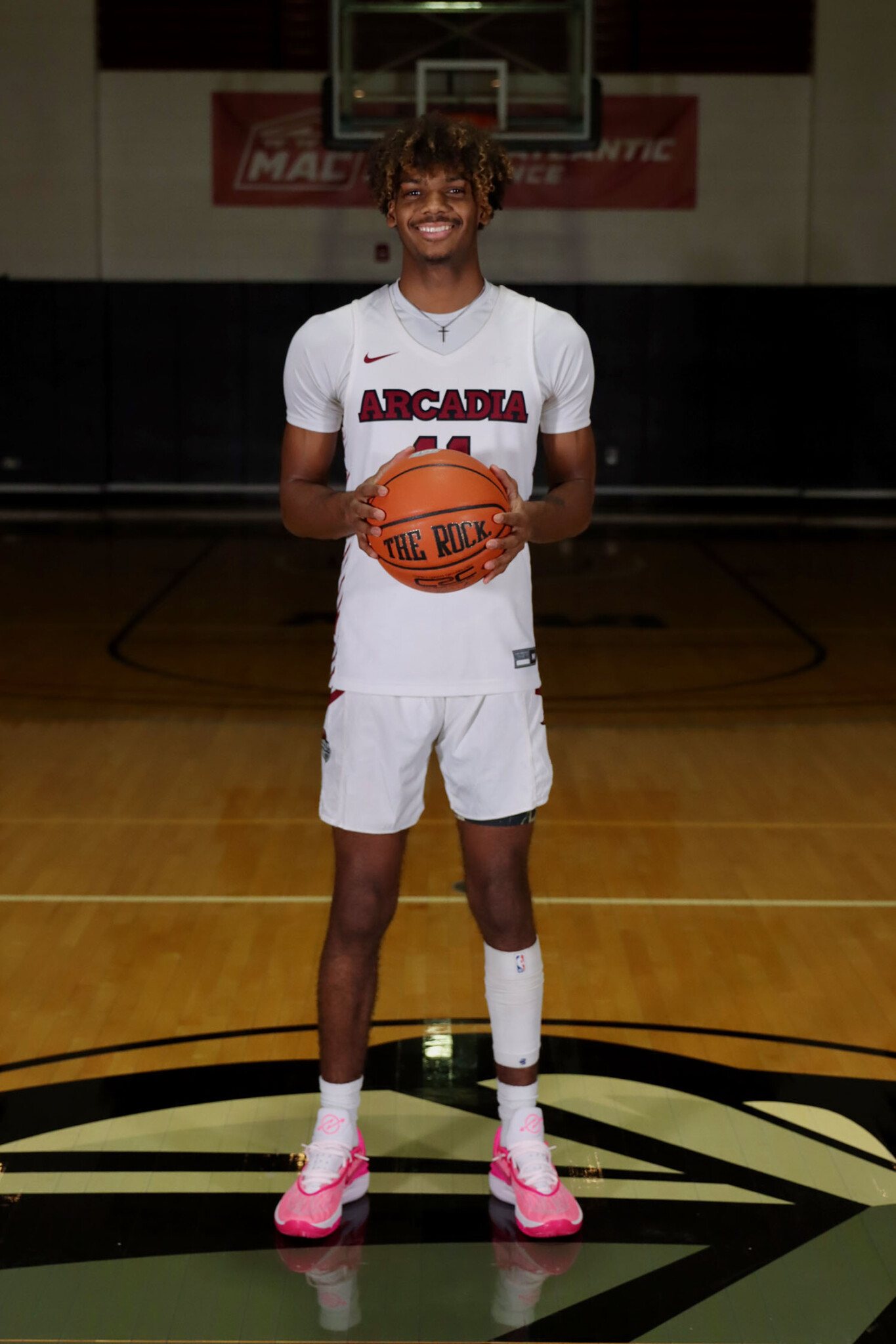 Debarrin Norman ’26 standing with a ball on Arcadia's basketball court.