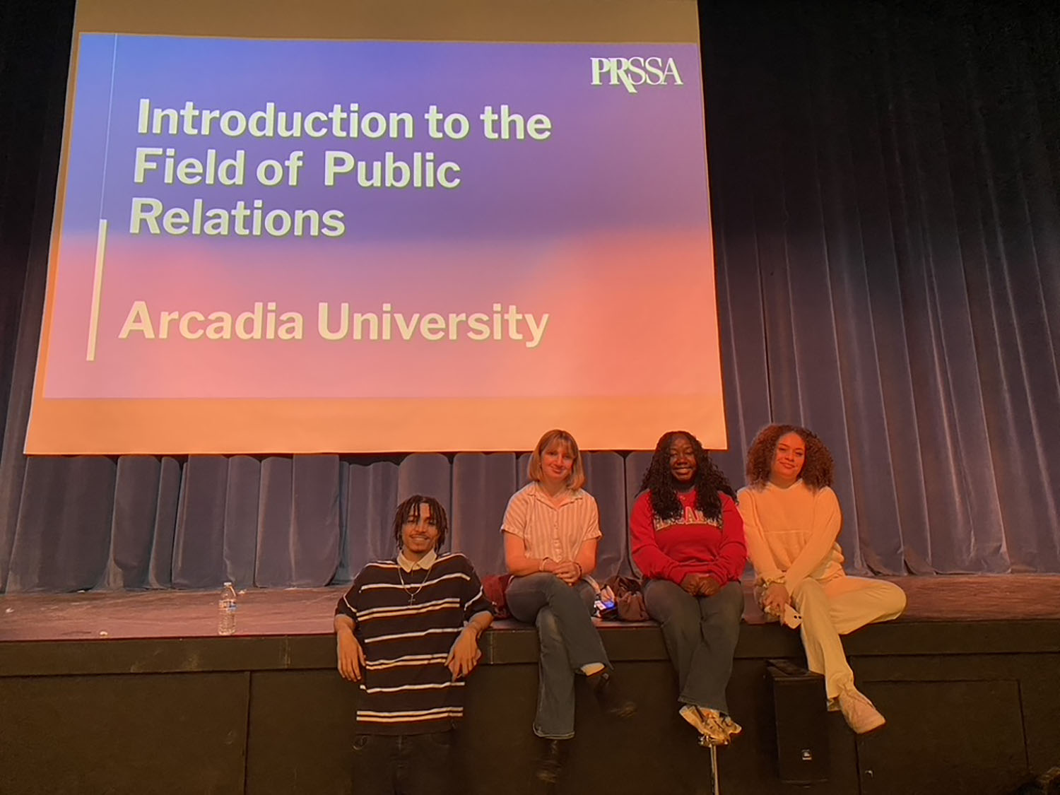 Students sitting in front of a screen that reads "Introduction to the Field of Public Relations - Arcadia University.