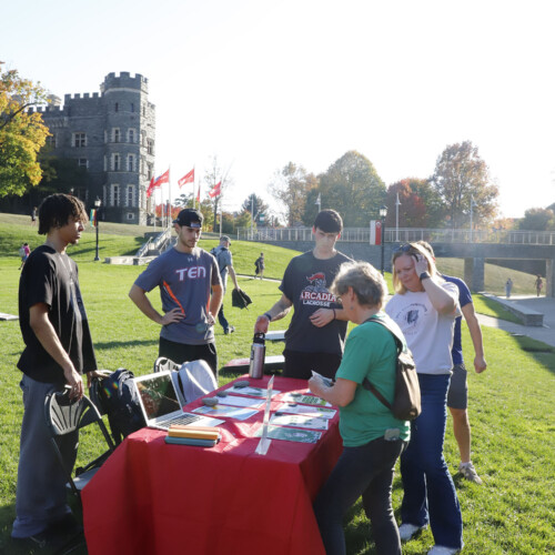 Students standing around a table with Dr. Chris Mullin and a guest on Haber Green.