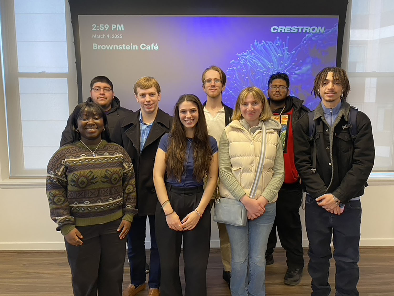 A group of students standing in front of a screen at Red Thread PR.