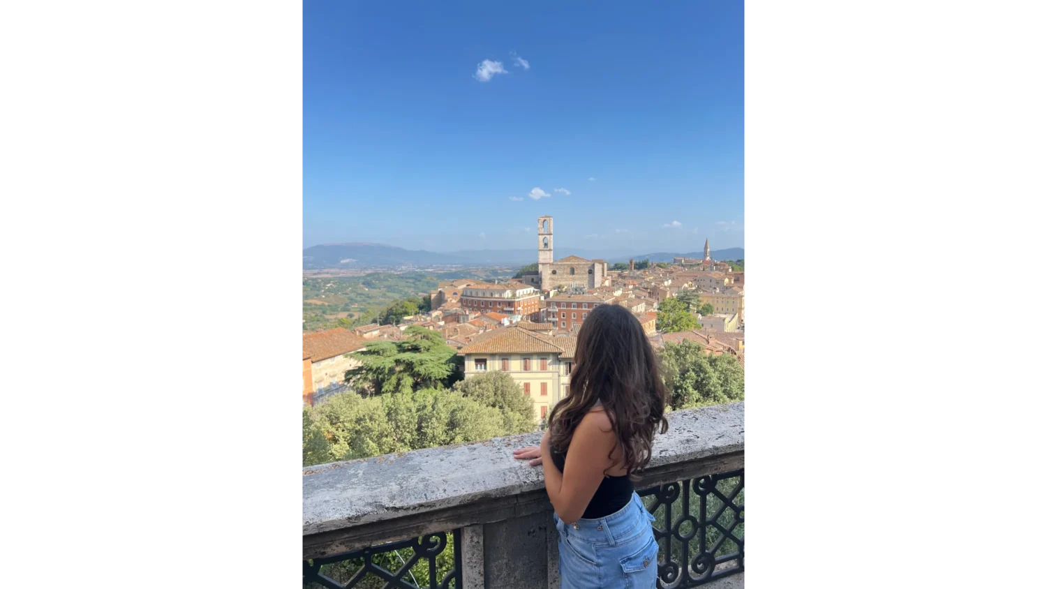 An Arcadia student looks over a stone railing towards the buildings in a town in Perugia, Italy.