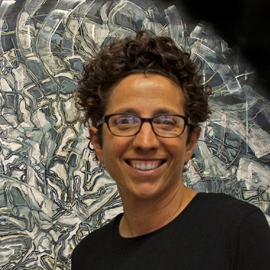 Nancy Agati smiling in front of art piece