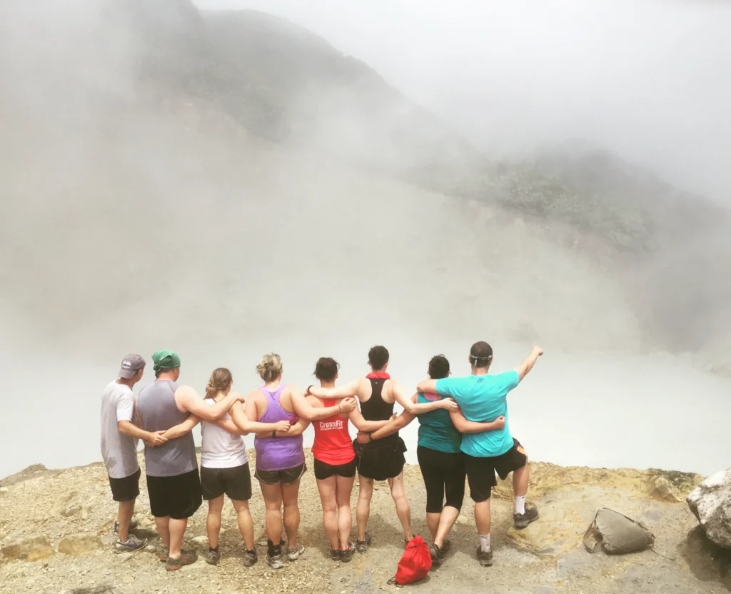 8 MBA students look over the Boiling Lake from atop a cliff with their backs facing the camera.