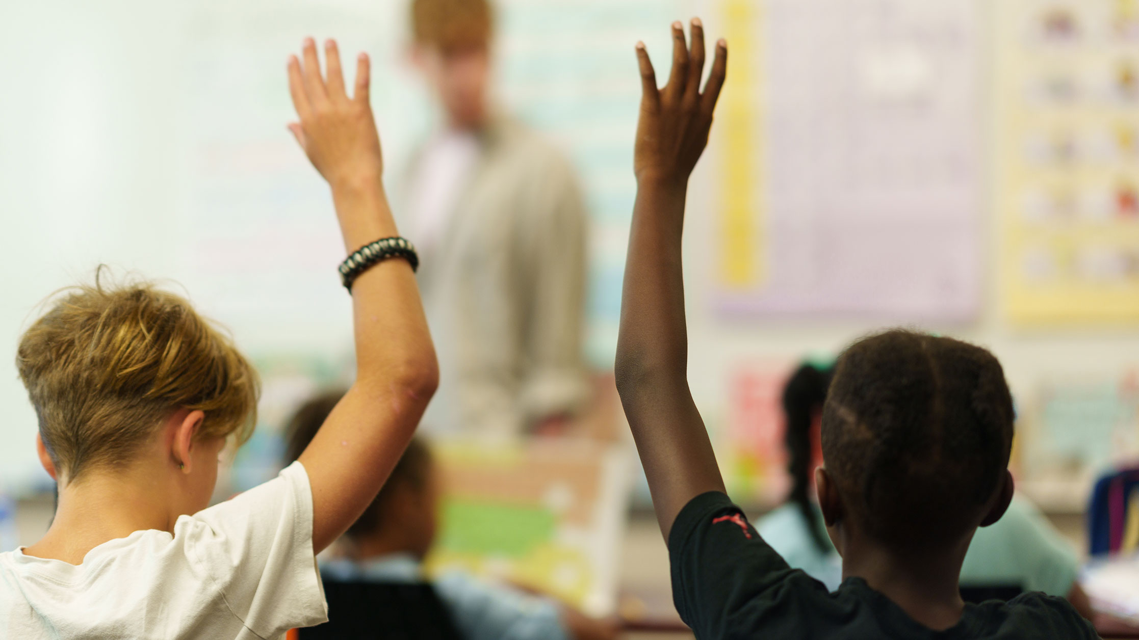 Two children raising hands in a classroom