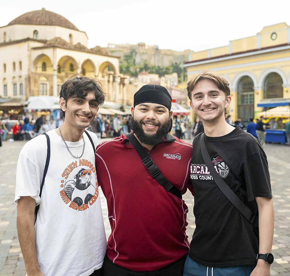 Three Arcadia students are standing in a Europen village square.