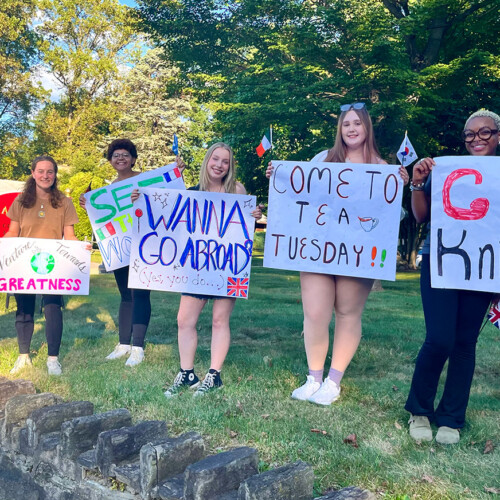 Lily Roberti ’28 and other STAMPs holding study abroad signs.