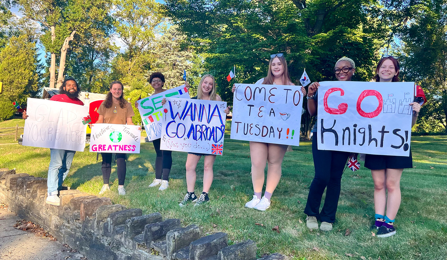 Lily Roberti ’28 and other STAMPs holding study abroad signs.