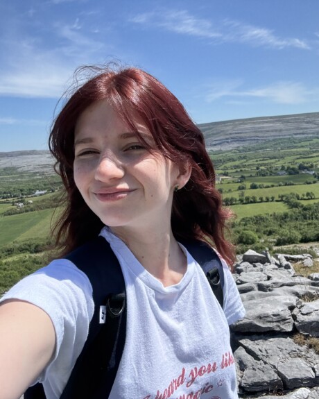 student in Ireland, green rolling hills, blue sky, selfie