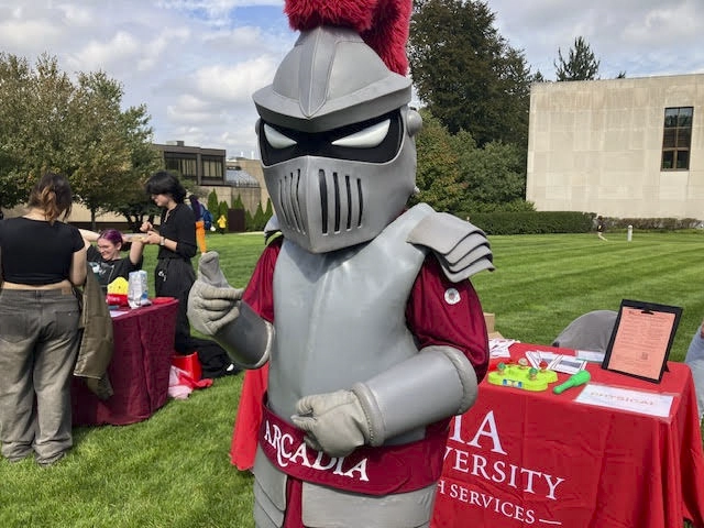 Archie stands by a display table during an outdoor health event on campus.