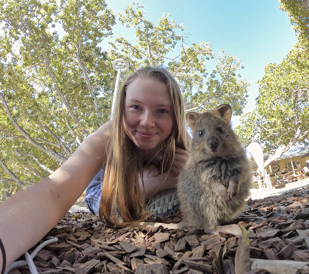 A fish eye lens view of Australia as a student poses with a wombat.