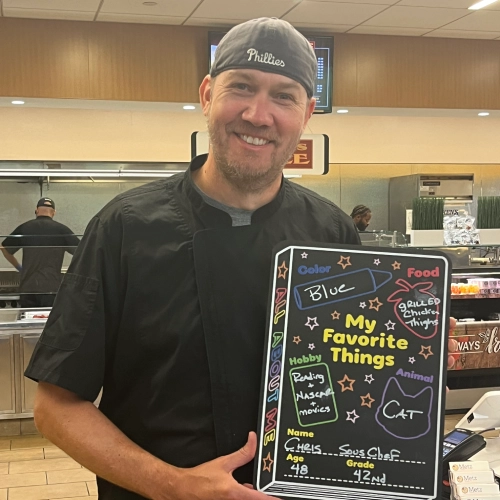 Chris Leube holding a "My Favorite Things" chalkboard.