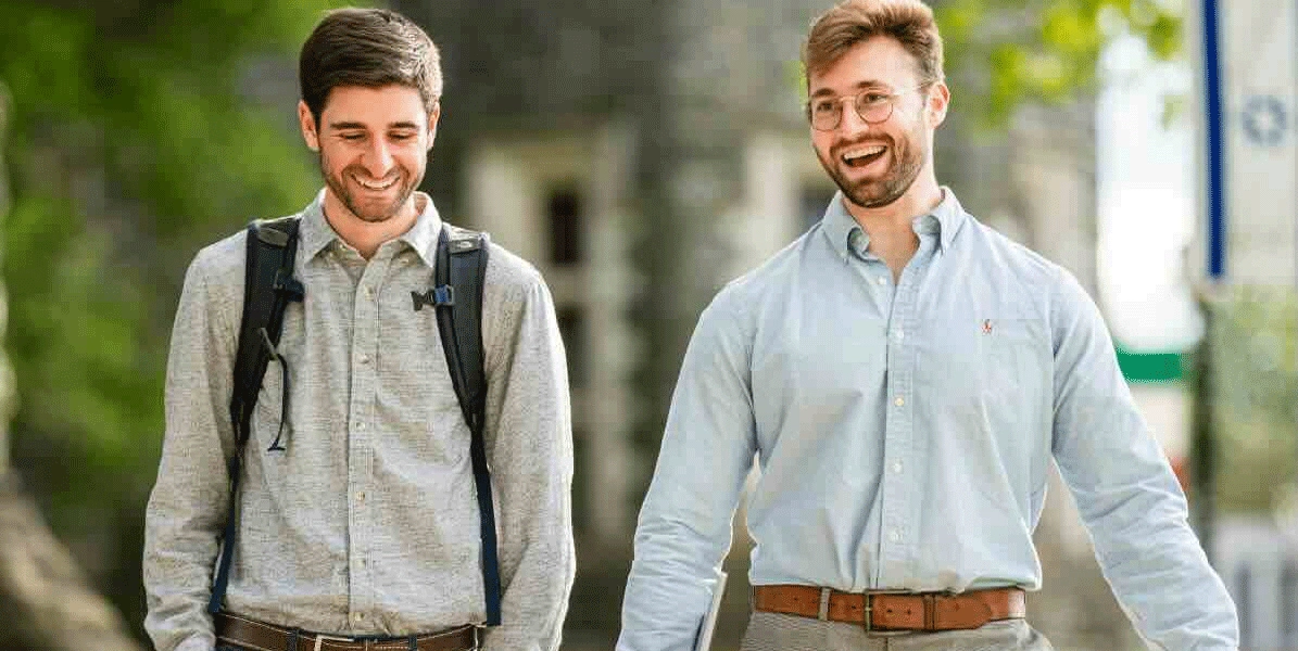 Two students walk around campus talking.