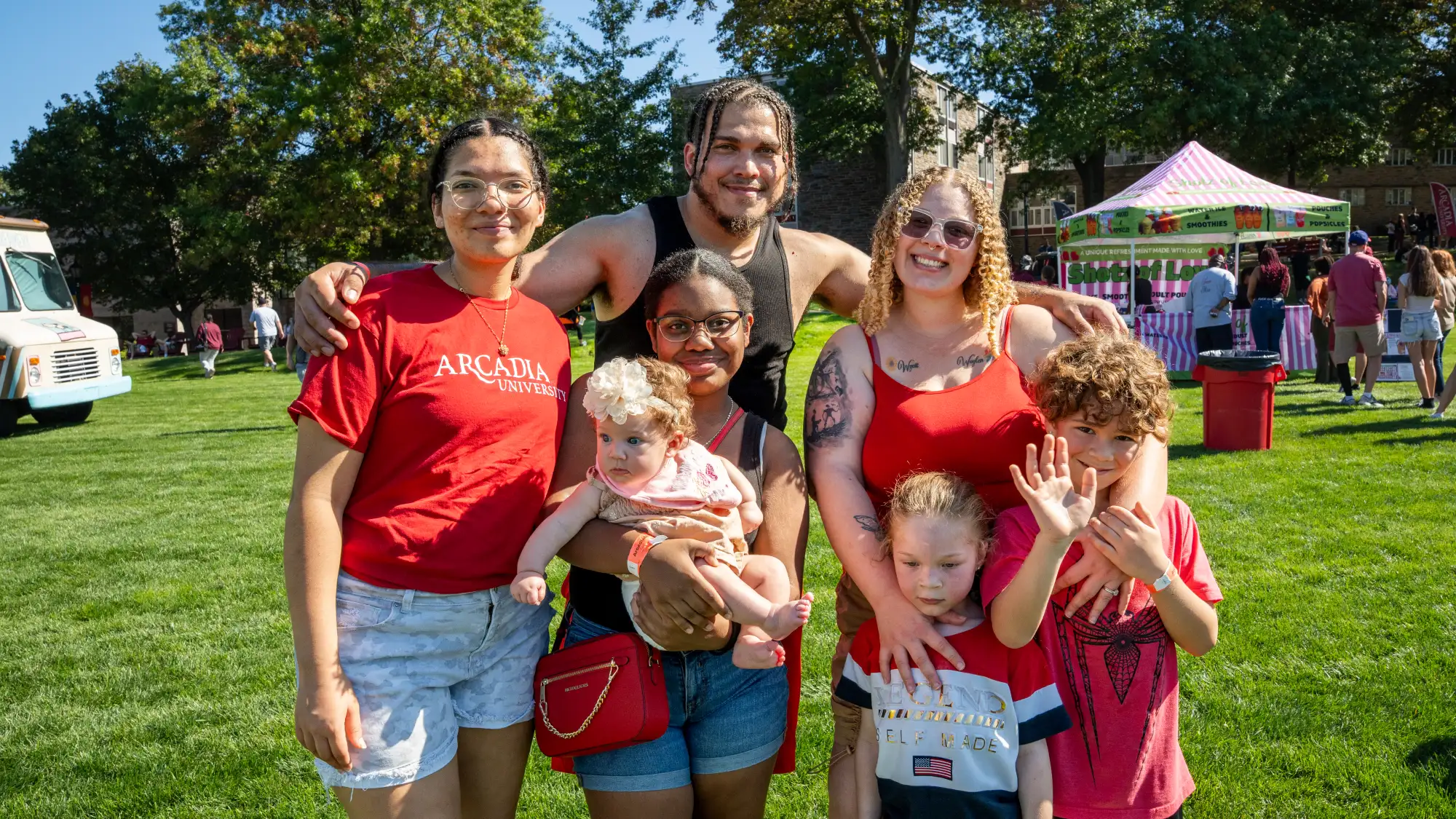 Four adults and two children pose for a photo at Arcadiafest while the woman in the center holds a baby.