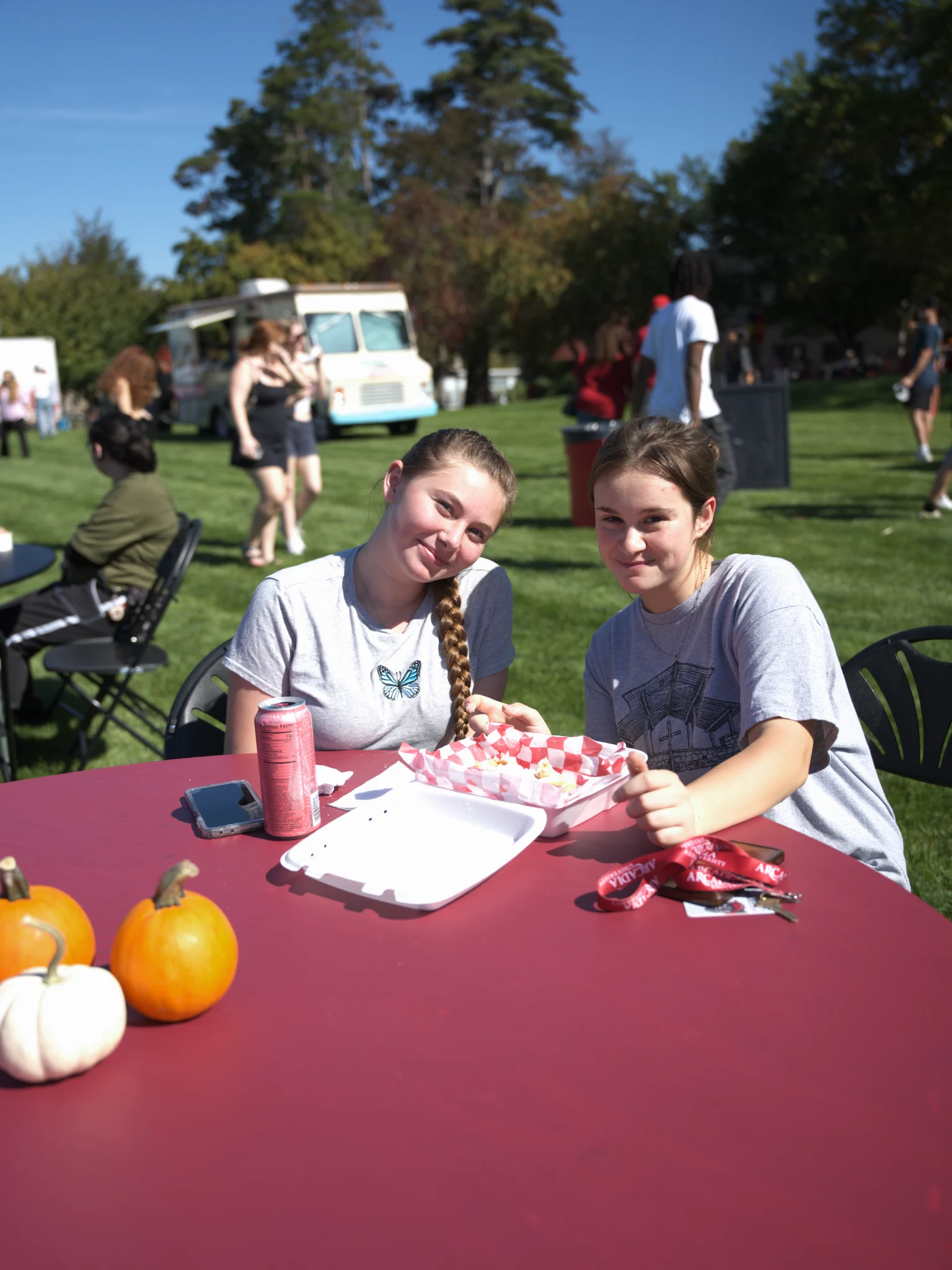 Two women pose for a photo while sitting at their table with food during Arcadiafest.